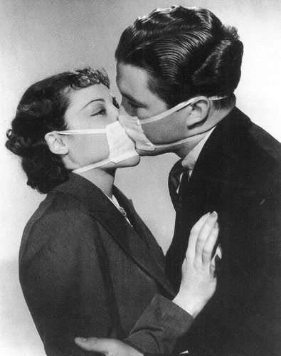 A man and woman wearing face masks and kissing