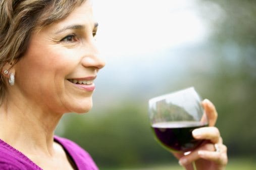 Smiling woman enjoying a glass of red wine